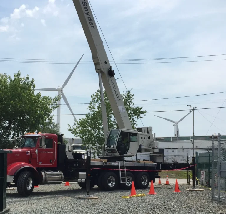 DJ Snyder red crane truck with its white boom raised on a job site near wind turbines