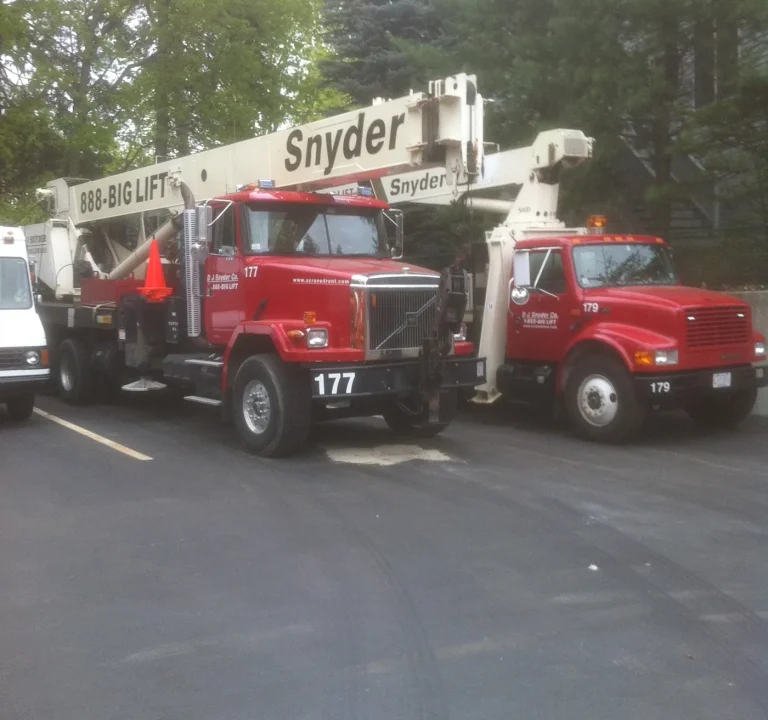 Two DJ Snyder red crane trucks, 177 and 179, with white Snyder 888-BIG-LIFT booms, parked side by side